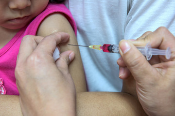Close-up hands, nurses are vaccinations to  children  using the syringe. Doctor vaccinating women...