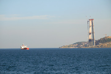 Container ship passing the new Third Bridge that is under construction on the Bosphorus, Istanbul, Turkey.