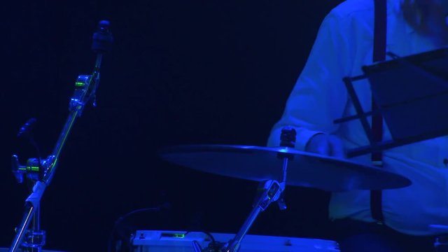Musician plays the drum set at concert. Close-up. Light of stroboscopes. 
