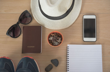 Naklejka premium Top view Concept travel accessories. Hat, book, phone, shoes, passport, sunglasses, on wooden background.