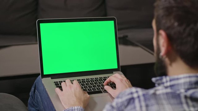 Close-up view of young man online shoping at home on pc, typing credit card number