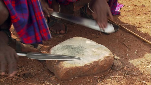 Close-up of Masai men sharpening weapons
