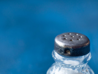Vintage salt bottle on dark blue background. Macro texture detail.