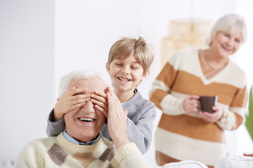 Boy covering his grandfather's eyes