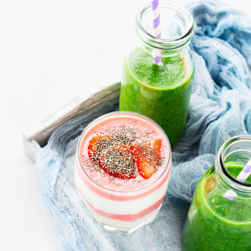 Healthy food concept green smoothie yogurt strawberries chia seeds breakfast on white gray tray blue textile. Fruit Vegetable juice glass bottle