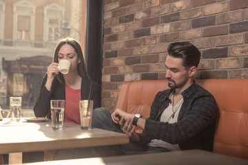 young woman man, drinking, looking at watch caffe