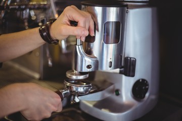 Waitress holding portafilter filled with ground coffee