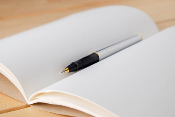pen and book on wood background