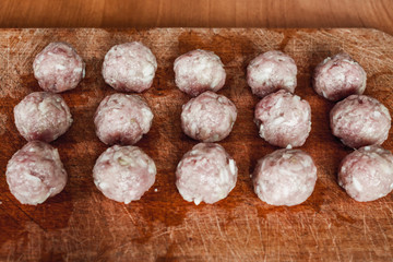 Home food, raw meatballs on a wooden board rural food