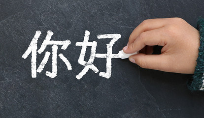 Enfant écrivant Bonjour en chinois à la craie sur une ardoise © lefebvre_jonathan