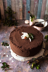 torta vegana al cocco ricoperta con strato di cioccolato fondente; decorazioni con piccoli boccioli di rosa