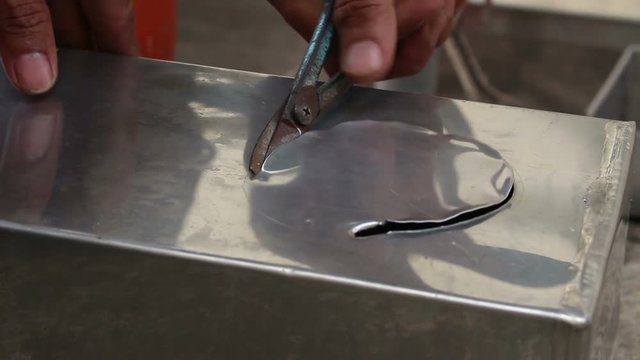 Technician cut aluminium plate by using scissors