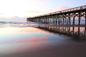 Fototapeta na wymiar Early morning at deserted atlantic ocean beach. Marine landscape with wooden pier in South Carolina, Myrtle Beach area, USA.