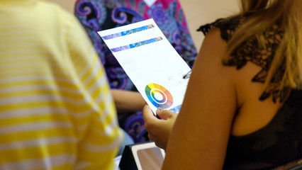 holding a white sheet of paper with colour chart