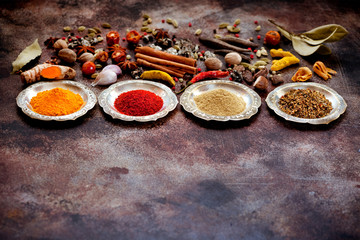 Spices and herbs in silver bowls on a rusty old background and space for text