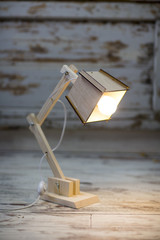 Homemade wooden table lamp on a background of cracked paint vintage wall