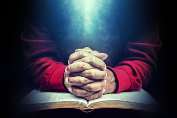 Praying hands on an open bible