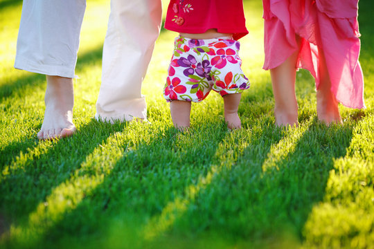 Dad mom and baby - happy family in colorful clothes barefoot on a juicy green lawn