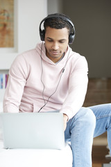 Enjoy the music. Afro American young man listening music on his laptop