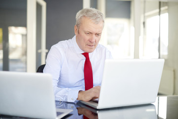 Financial analysis. Senior businessman working hard on laptop at office