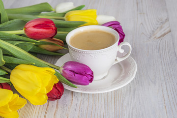 Fototapeta na wymiar cup of coffee and muliti colored tulips