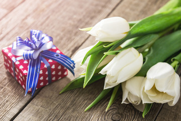 White tulips and gift box on wooden table