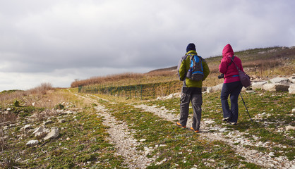 Obraz premium Man and woman hikers trekking in mountains. Young couple walking with backpacks in mountains.
