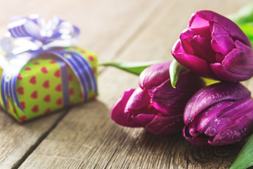 Pink tulips and gift box on wooden table