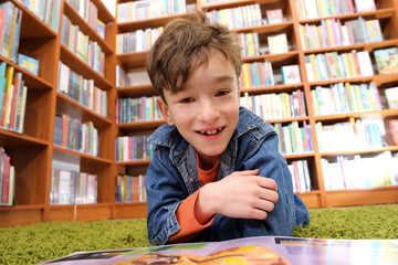 Cute boy reading book in library
