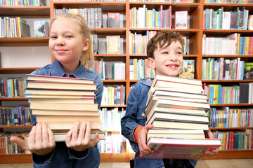 Cute boy and girl  reading book in library

