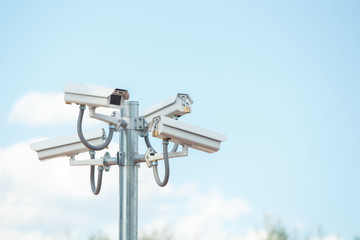 Four CCTV under blue sky for city security.