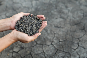 Hand holding soil over dry and crack soil because no water long time at here.