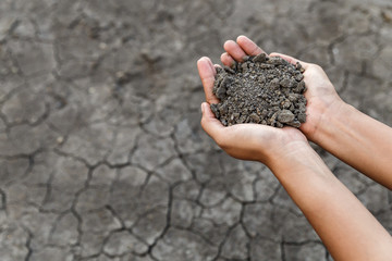 Hand holding soil over dry and crack soil because no water long time at here.
