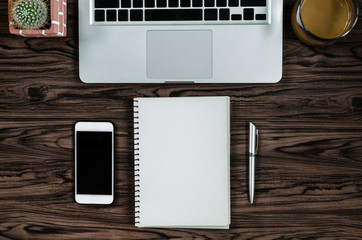 Brown wood office desk table with a book, pen, cactus and phone for working in top view and copy space.