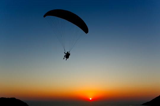 Paraglider silhouette against the background of the sunset sky