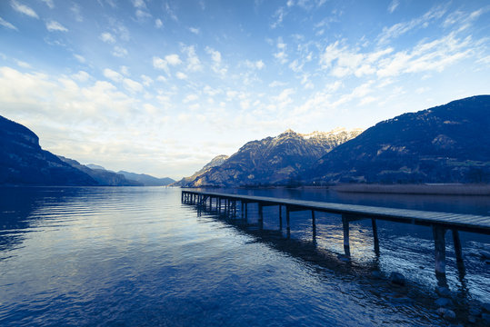 Wooden pier. Mountain lake landscape in the evening. Sky over lake.