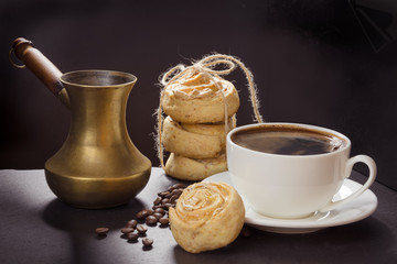 Cup of black coffee and old copper cezve and with cookies on black slate dish. Coffee break.