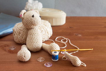 Crochet toy bear in the process with accessories and materials: yarn, hook, row counter