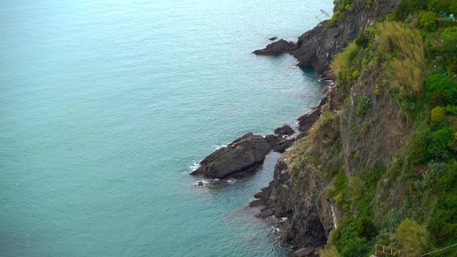 People are sitting on a rock and waiting before they jump in the mediterranean sea, in the Cinque Terre, Italy