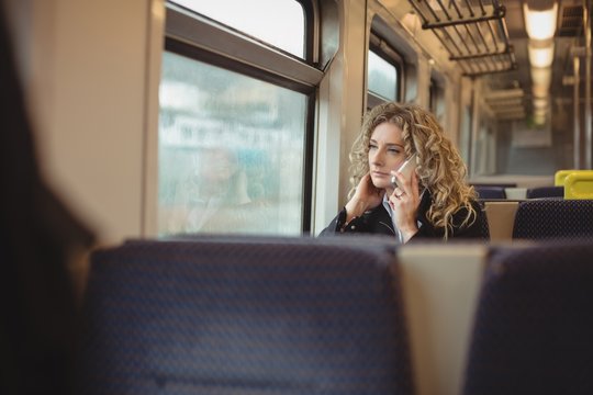 Woman talking on mobile phone inside train compartment