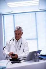 Fototapeta premium Doctor sitting at tablet and using mobile phone