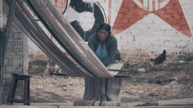 Indigenous woman working on an handmade loom on the streets of Cajamarca, Peru
