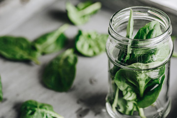 Spinach leaves in jar on grey background
