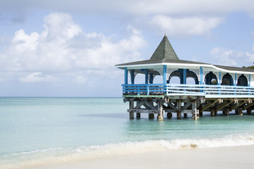 covered pier in the ocean with blue sky and sea