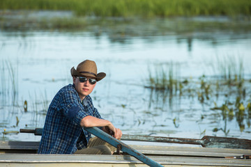 A man in a cowboy hat and sunglasses in a rowing boat