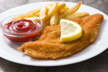 Wiener schnitzel with fried potatoes on wooden background
