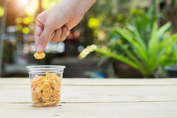 Hand hold corn flake on wooden table
