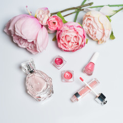Perfume bottle, nail polish, lipstick. Fashion woman still life. Pop female things with flowers on white background.