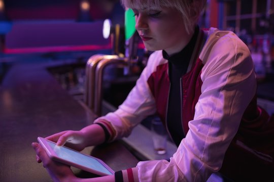 Female bartender using digital tablet at bar counter