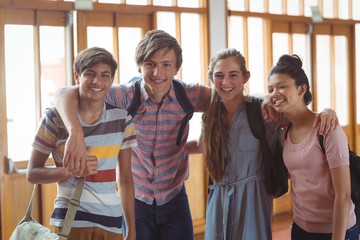 Portrait of happy students standing with arms around in campus